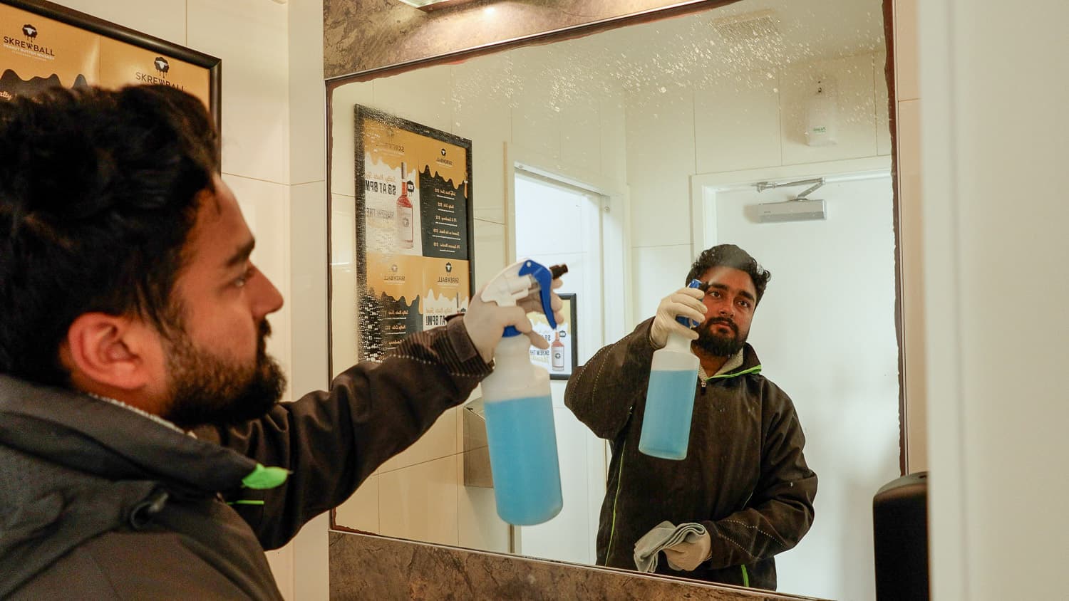 Team Member cleaning the bathroom mirror